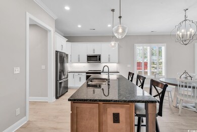 Kitchen with stainless steel appliances, a breakfast bar, a sink, baseboards, and tasteful backsplash