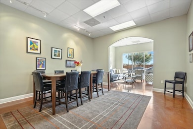 Dining area with rail lighting, arched walkways, baseboards, and finished concrete flooring