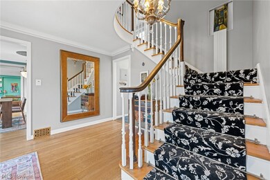 Stairs with light hardwood / wood-style flooring, a chandelier, and ornamental molding