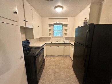 Kitchen featuring black appliances, open shelves, tasteful backsplash, and white cabinetry