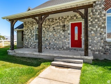 Property entrance with stone siding, a shingled roof, a porch, and a lawn