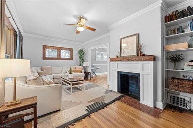 The living room features built-in shelving, a fireplace, crown molding, and refinished hardwood floors