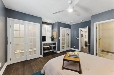 Bedroom 1 with french doors, wood finished floors, multiple closets, and a ceiling fan