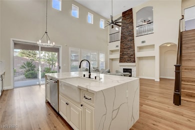 Kitchen with stainless steel dishwasher, a towering ceiling, a sink, and ceiling fan with notable chandelier