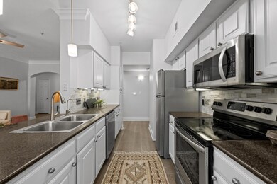 Kitchen with arched walkways, white cabinetry, ap