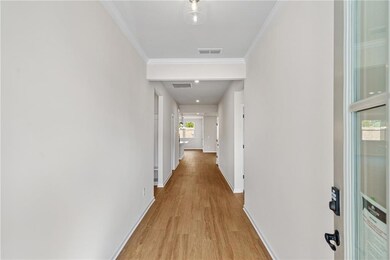 Hallway with crown molding and light hardwood / wo