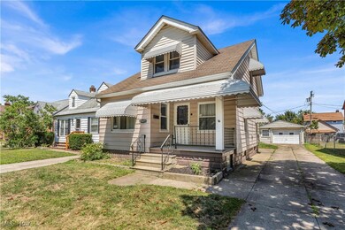 View of front facade featuring a front yard, an outdoor structure, a porch, and roof with shingles