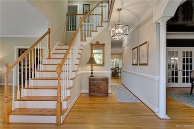 Stairway featuring a notable chandelier, columns,