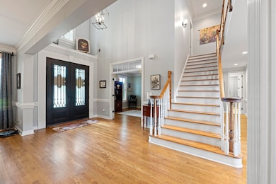 Enter through the grand double custom iron doors into a soaring two-story foyer, where gleaming hardwood floors and intricate crown molding set the tone for the refined interiors that await.