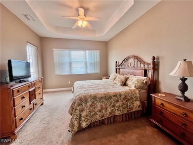 Carpeted bedroom with a King Bed, Access to the balcony, water facing views, ceiling fan, tray ceiling and ensuite bathroom with his/hers walk in closets