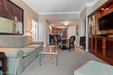 Living area with crown molding, baseboards, and li