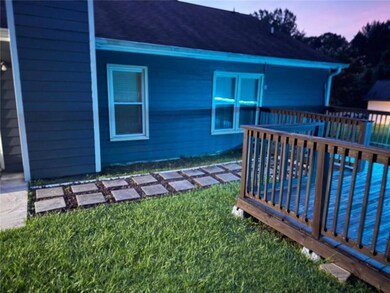 Back of house at dusk with a deck, a yard, and roof with shingles