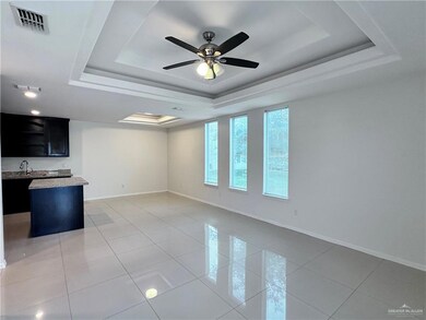 Unfurnished living room with light tile patterned floors, visible vents, a raised ceiling, and baseboards