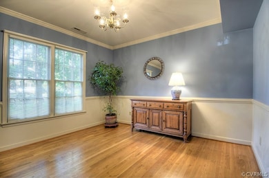 Formal Dining Room with Hardwood floor, crown molding, chair rail, overhead lighting and great view to front yard