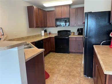 Kitchen featuring black appliances, light countertops, and a peninsula
