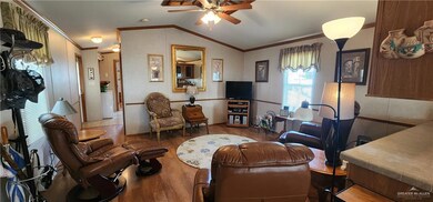 Living room featuring lofted ceiling, a ceiling fan, ornamental molding, and wood finished floors