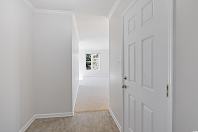 Corridor with light wood-type flooring and crown molding