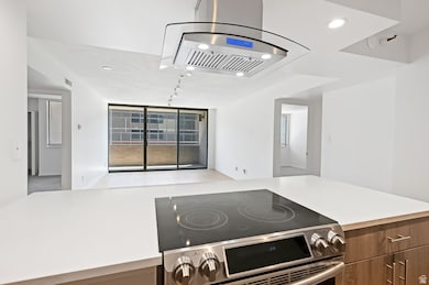 Kitchen featuring electric range, island range hood, recessed lighting, open floor plan, and brown cabinetry
