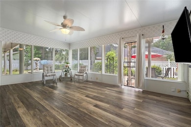Sunroom with wood-type flooring, healthy amount of natural light, and wallpapered walls