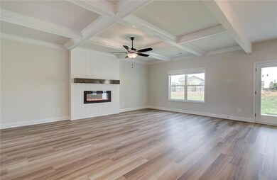 Unfurnished living room with beamed ceiling, coffered ceiling, light wood-style floors, a fireplace, and ceiling fan