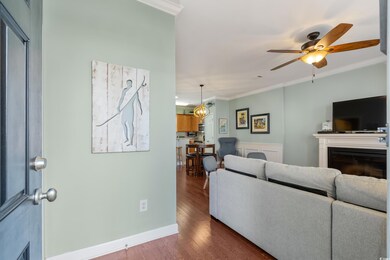 Living area featuring a ceiling fan, a fireplace, baseboards, ornamental molding, and dark wood-style floors