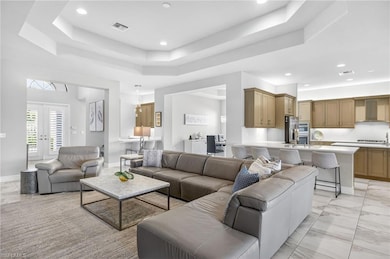 Living area with a raised ceiling, light marble finish flooring, recessed lighting, and french doors
