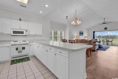 Kitchen featuring white appliances, a peninsula, light countertops, vaulted ceiling, and a ceiling fan
