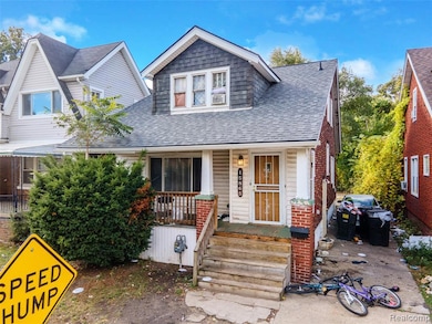 Duplex featuring roof with shingles, a porch, and brick siding