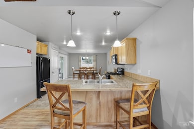 Kitchen with a breakfast bar, light brown cabinets, hanging light fixtures, black appliances, and a peninsula