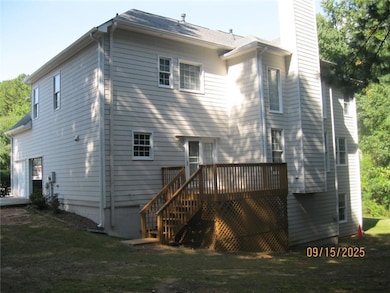 Back of house with a chimney, stairway, a deck, and a lawn