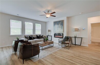 Living area featuring a glass covered fireplace, a ceiling fan, and light wood-style floors