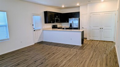 Kitchen with dark cabinets, appliances with stainless steel finishes, dark wood finished floors, a peninsula, and recessed lighting