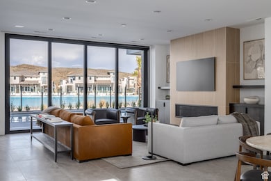 Living area with a wall of windows, a glass covered fireplace, and light tile patterned floors