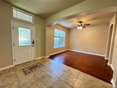 Tiled entryway with arched walkways, ceiling fan,