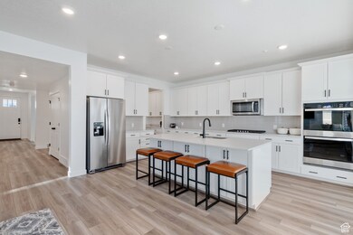 Kitchen with stainless steel appliances, backsplash, light countertops, recessed lighting, and a breakfast bar area