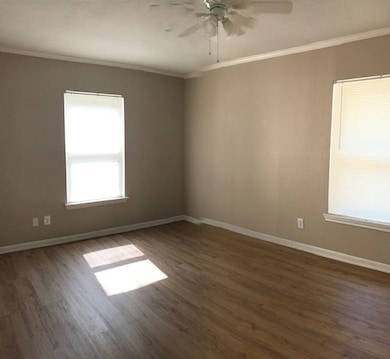 Spare room with crown molding, dark wood-style floors, and ceiling fan