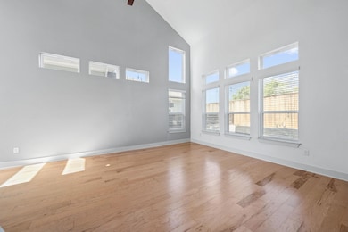 Spare room with wood-type flooring, high vaulted ceiling, and a ceiling fan