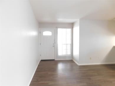 Foyer featuring dark wood-type flooring and baseboards