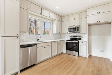 Kitchen with appliances with stainless steel finishes, light wood-type flooring, tasteful backsplash, and sink