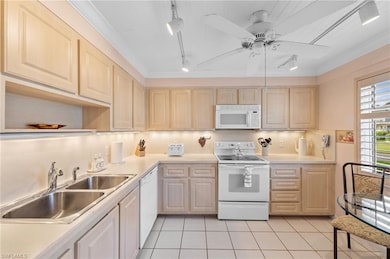 Kitchen featuring white appliances, rail lighting, light countertops, light brown cabinetry, and light tile patterned flooring