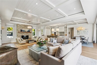 Living room featuring coffered ceiling, a stone fi