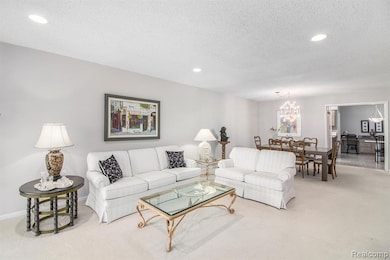 Carpeted living room featuring recessed lighting, a textured ceiling, and a chandelier