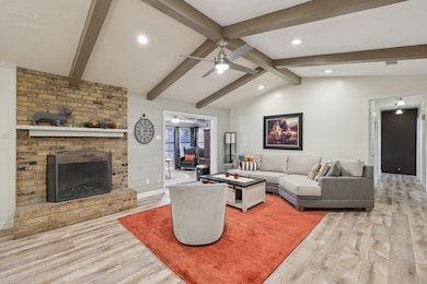 Living area featuring a brick fireplace, light wood finished floors, ceiling fan, and recessed lighting