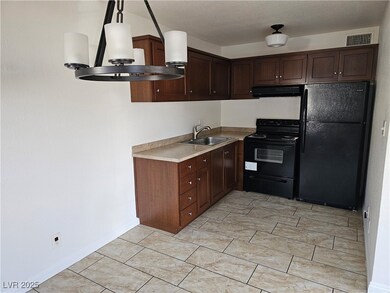 Kitchen with black appliances, dark brown cabinets, light countertops, extractor fan, and pendant lighting
