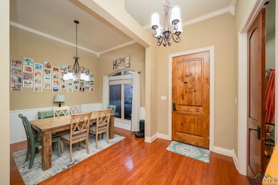 Dining area with a chandelier, crown molding, and wood finished floors