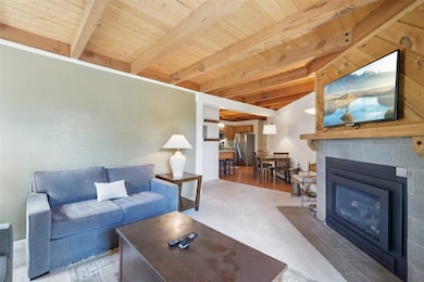 Living area with a wood ceiling with exposed beams and a fireplace