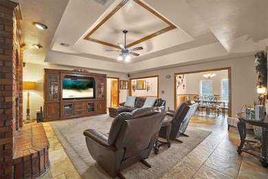 Living room with a tray ceiling, a chandelier, and ceiling fan
