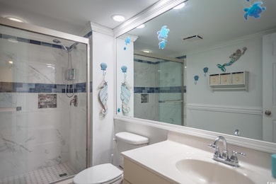 Full bath featuring vanity, a marble finish shower, and ornamental molding