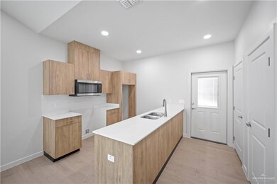 Kitchen with visible vents, modern cabinets, stainless steel microwave, light wood-style floors, and a sink