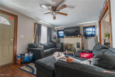 Living area featuring wood finished floors, a textured ceiling, a fireplace, and ceiling fan.